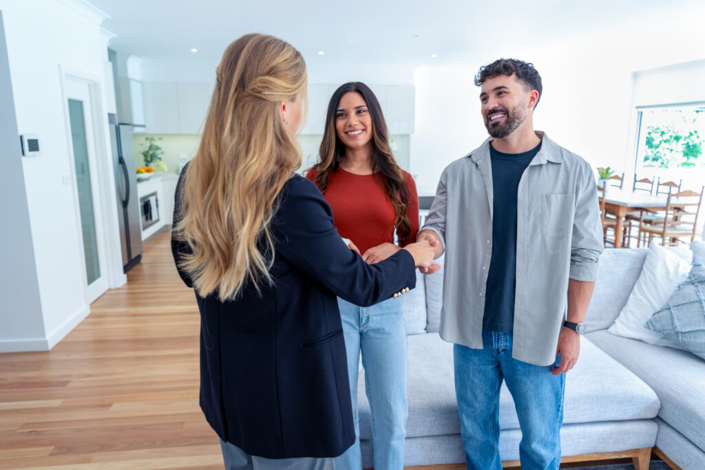 Real estate agent with couple in luxury home. They are shaking hands.